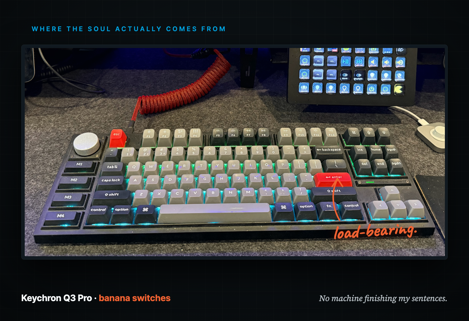 A Keychron Q3 Pro mechanical keyboard with red escape and enter keys and blue-green backlighting on a dark desk, a coiled red cable running off to the left.