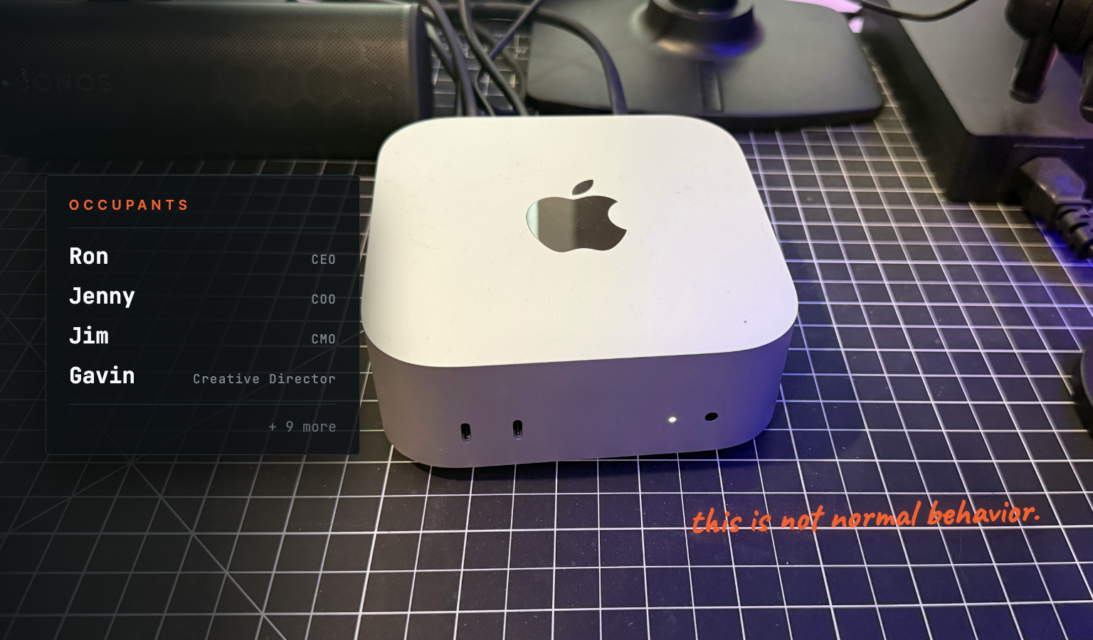 A Mac Mini on a cutting mat, captioned with a building directory listing Ron, Jenny, Jim and Gavin as its occupants, plus nine more.
